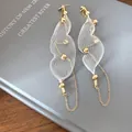 Vista ravvicinata di eleganti orecchini a nappa lunga con rete bianca e accenti di perline d'oro. - Stile Maglia con Nappina Lunga / Oro-Argento
