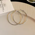 Close-up of minimalist silver hoop earrings with a polished metal finish on a cream plate. - 4cm / Silver