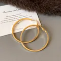 Detail shot of large gold-tone hoop earrings on a textured background with a prop card - Medium-Large (HE23305) / Diameter 50mm / Gold