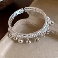 Close-up of ethnic style silver open bangle with multiple delicate hanging bell charms - Bell Tassel Open Style / Silver
