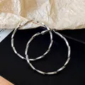 Dettaglio squisito di orecchini a cerchio geometrici argentati con design a spirale - Stile Intrecciato / Argento