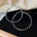 Primo piano di orecchini a cerchio geometrici argentati con un design sfaccettato e moderno - Stile di Taglio Geometrico / Argento