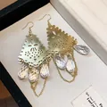Detailed view of gold filigree earrings with clear glass waterdrop pendants in a box - Hook Style / Gold