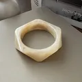 Vista detallada que muestra la elegante forma hexagonal y la textura de mármol de este brazalete - Estilo Hexagonal / Beige