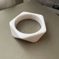 Detalle de una pulsera hexagonal minimalista de acrílico blanco con acabado liso y brillante - Estilo Hexagonal / Rosa Claro