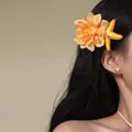 Detailed view of orange fabric flower and yellow starfish hair clip on long dark hair - Duckbill Clip (6#) / Yellow-Orange