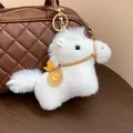 Close-up detail of a cute white plush horse keychain charm on a brown quilted handbag - Charm / White