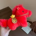 Close-up of a red plush horse keychain with a gold ingot on a lifestyle background - Charm / Red