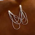 Minimalist layered silver tassel earrings displayed on a textured brown fabric background - Silver Pin Tassel Style / Silver