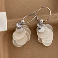 Detail of round shell tassel earrings with silver finish and sparkling zirconia stone - Silver and White
