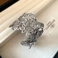Detailweergave van een vintage zilveren metalen manchetarmband met opengewerkt bloemmotief. - Armring (HB4380) / Zilver