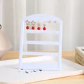 Vista detallada de un soporte para pendientes blanco minimalista con elegantes pendientes rojos y oro - 24 Agujeros / Blanco