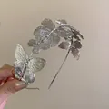 Close-up showing the detailed silver butterfly embellishments on a metal headband - Silver