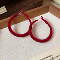 Primo piano di orecchini a cerchio floccati rossi con elegante texture in velluto - Ago d'argento / Rosso