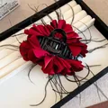 Detailansicht einer eleganten Vintage-Haarklammer mit roten Rosen und schwarzen Federn - Rot