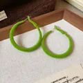 Primo piano di orecchini a cerchio floccati verde vibrante con eleganti dettagli. - Ago d'argento / Verde
