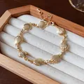 Detailed view of a vintage gold-tone shell link bracelet resting in a jewelry display box - Gold