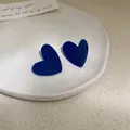 Eleganti orecchini a cuore floccati blu Klein esposti su un piatto di ceramica bianca - Orecchini a Bottone a Cuore Floccato / Blu Klein