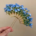 Macro view of an elegant blue gypsophila floral hairpin with a gold-tone U-shaped frame - Blue