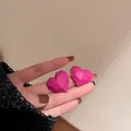 Eleganti orecchini a perno a cuore sfaccettati geometrici fucsia opachi sulla mano - Orecchini a Bottone Cuore 3D Geometrici / Rosa Rosso