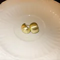 Close-up of golden brushed geometric bean stud earrings displayed on a white plate - Gold