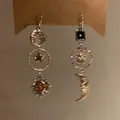 Close-up detail of asymmetric sun and moon tassel ear hooks with a vintage metal finish. - Asymmetrical Star & Moon Tassel / Gold-Silver