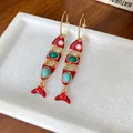 Gros plan d'élégantes boucles d'oreilles en émail rouge en forme de poisson avec pierres - Style Pendentif Poisson (WE3846)