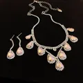 Close-up of iridescent teardrop rhinestone jewelry set with pavé details on black background. - Necklace and Earring Set / Silver
