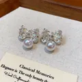 Detailed macro view of silver wrinkled bow earrings with elegant white pearl drops - Pleated Bow Pearl Style / Silver