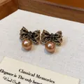Detail view of vintage gold wrinkled bow-knot stud earrings with brown pearl drops. - Pleated Bow Pearl Style / Coffee Gold