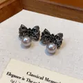 Detailed view of pleated dark metallic bow earrings featuring elegant grey pearl drops - Pleated Bow Pearl Style / Black