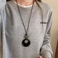 Gros plan d'un long collier de style Zen avec pendentif circulaire noir sur un sweat - Collier Texture Anneau (30#)