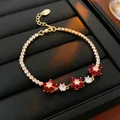 Élégant bracelet en or avec fleurs en zircon rouge et blanc sur un présentoir noir raffiné - Style Fleur Rouge / Or