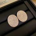 Gros plan détaillé de boucles d'oreilles ovales pavées de strass dorés élégants - Style Ovale / Or