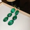 Detailed macro view of retro emerald green faceted drop earrings in a jewelry box - Dark Green Triple Layer Drop