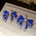 Elegant dark blue resin bow earrings with sparkling clear rhinestones on a gray velvet tray - Silver Blue