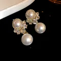Close-up of vintage royal style earrings with white pearls and sparkling rhinestones - Earrings / 925 Silver Needle / Gold with White Pearl