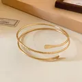 Detailed macro view of a gold spiral open bangle featuring textured and smooth metal finishes - Minimalist Spiral / Gold