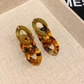 Close-up of chunky chain earrings with gold metal and tortoiseshell resin links - Earrings / Gold & Coffee