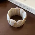 Close-up of a retro marble-patterned stretch bracelet with stylized H-motif links - Cream White H-Shape