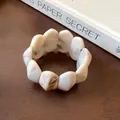Close-up of retro cream marbled oval bead elastic bracelet on a wooden surface - Cream White Style 1