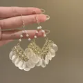 Detailed shot of elegant gold earrings with white pearls and iridescent shell charms - Ear Hook Style (Style 6) / White