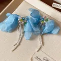 Vista dettagliata di orecchini a fiore in tessuto blu con frange di perline e accenti colorati. - Stile con Perno in Argento (Style 29)