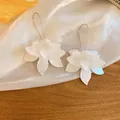 Dettaglio macro di eleganti orecchini a fiore in tessuto bianco con ganci in argento - Stile 47# / Ganci per orecchini / Bianco