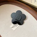 Close-up of a stylish glossy black resin flower hair clip on a textured fabric background. - Flower Style (8#)
