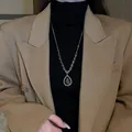 Gros plan d'un collier avec pendentif en zircone poire porté sur un col roulé noir. - Collier (9)