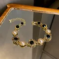 Vue détaillée d'un élégant bracelet en or avec perles, cristaux noirs et strass. - Style Tournesol en Strass / Or