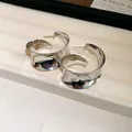 Close-up of minimalist silver wide metallic C-shaped hoop earrings on display tray - Silver