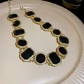 Elegant vintage gold-plated necklace with black square and round gemstones on a plate - Necklace Style 37