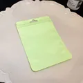 Close-up of a lime green resealable mylar bag for jewelry packaging on a white plate. - Plastic Self-Sealing Bag / Avocado Green
